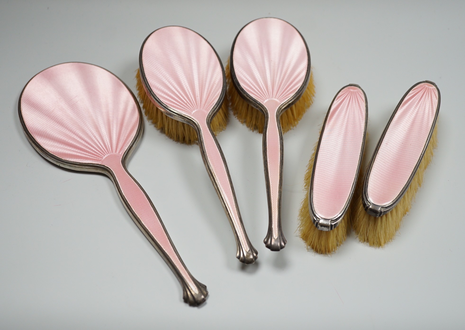 A George V five piece silver and pink guilloche enamel dressing table mirror and brush set, by Adie Brothers.